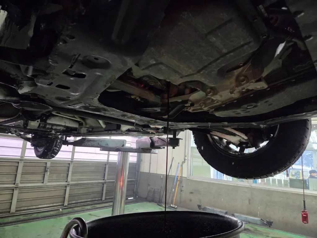 ホワイトパールの日産セレナをリフトアップしてエンジンオイルを抜き取っている写真