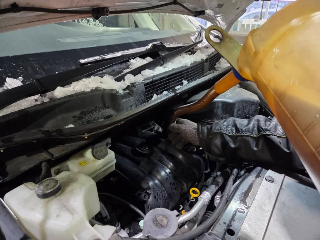 エンジンオイルを抜き取ったホワイトパールの日産セレナに新たなエンジンオイルを注いでいる写真