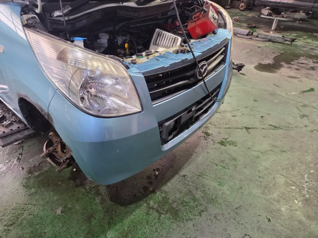 マツダ・フレア（ブルー）のフロント部分。ボンネットを開け、前輪を外している状態